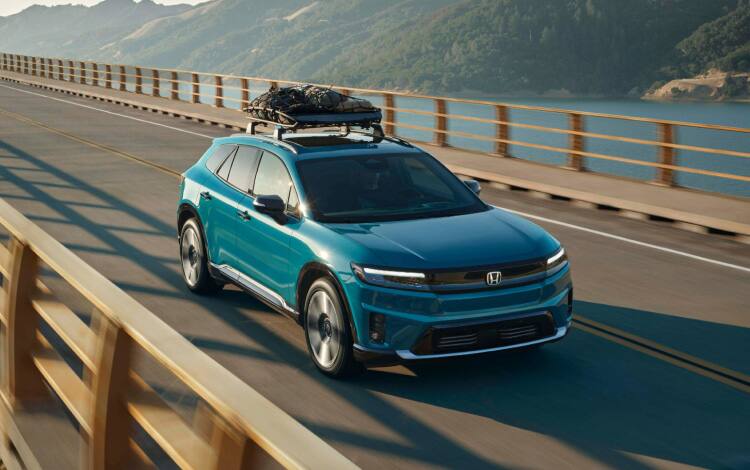 2026 Honda Prologue Elite in North Shore Pearl crossing a bridge in afternoon light, featuring Honda Genuine Accessories.